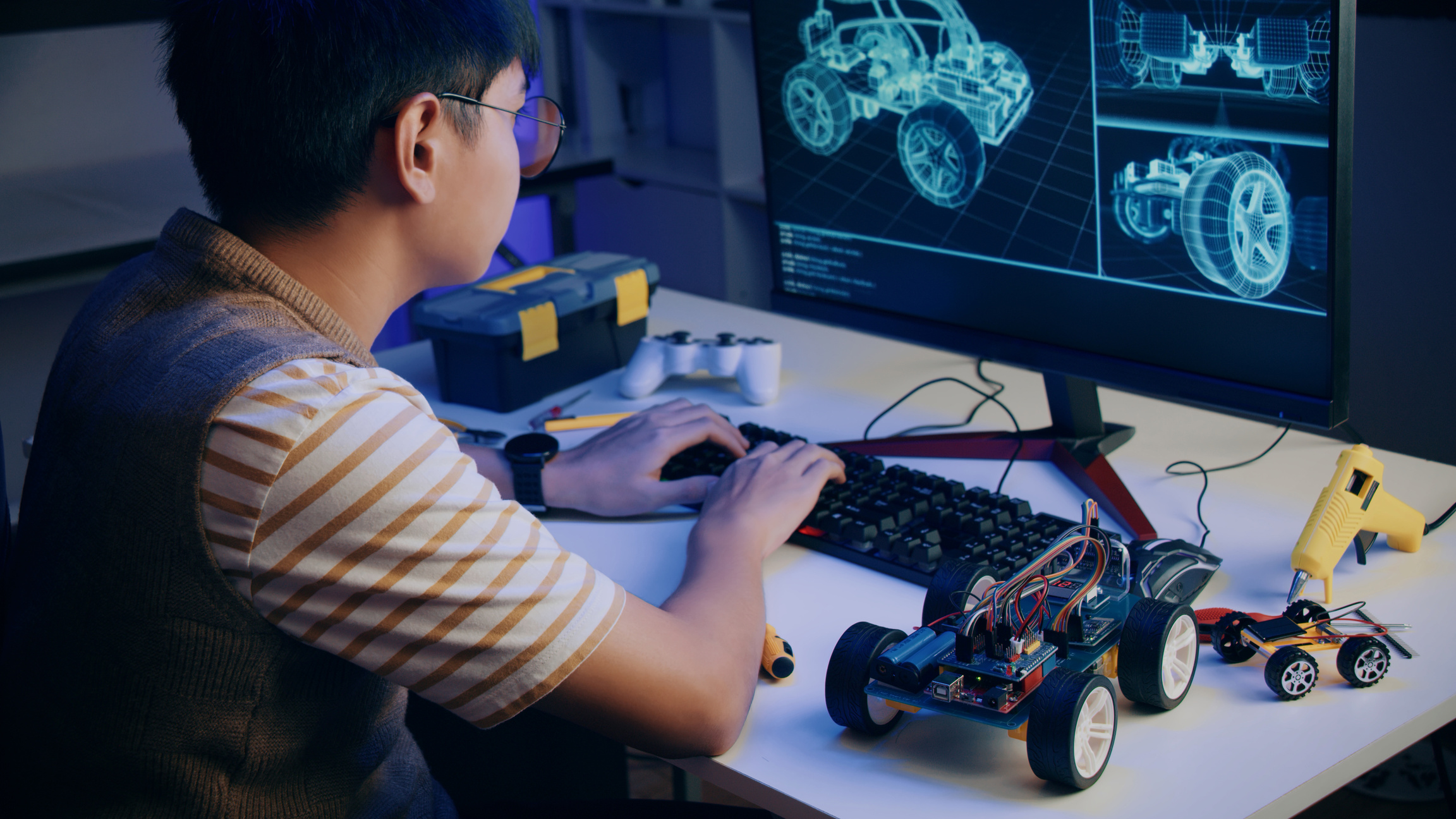 Asian teenager doing Arduino robot homework project in house